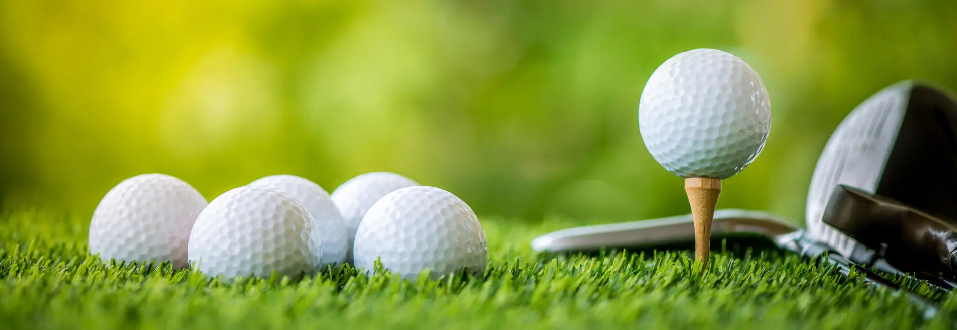 White golf balls on green grass with a golf club, symbolizing healthy golf snacks.