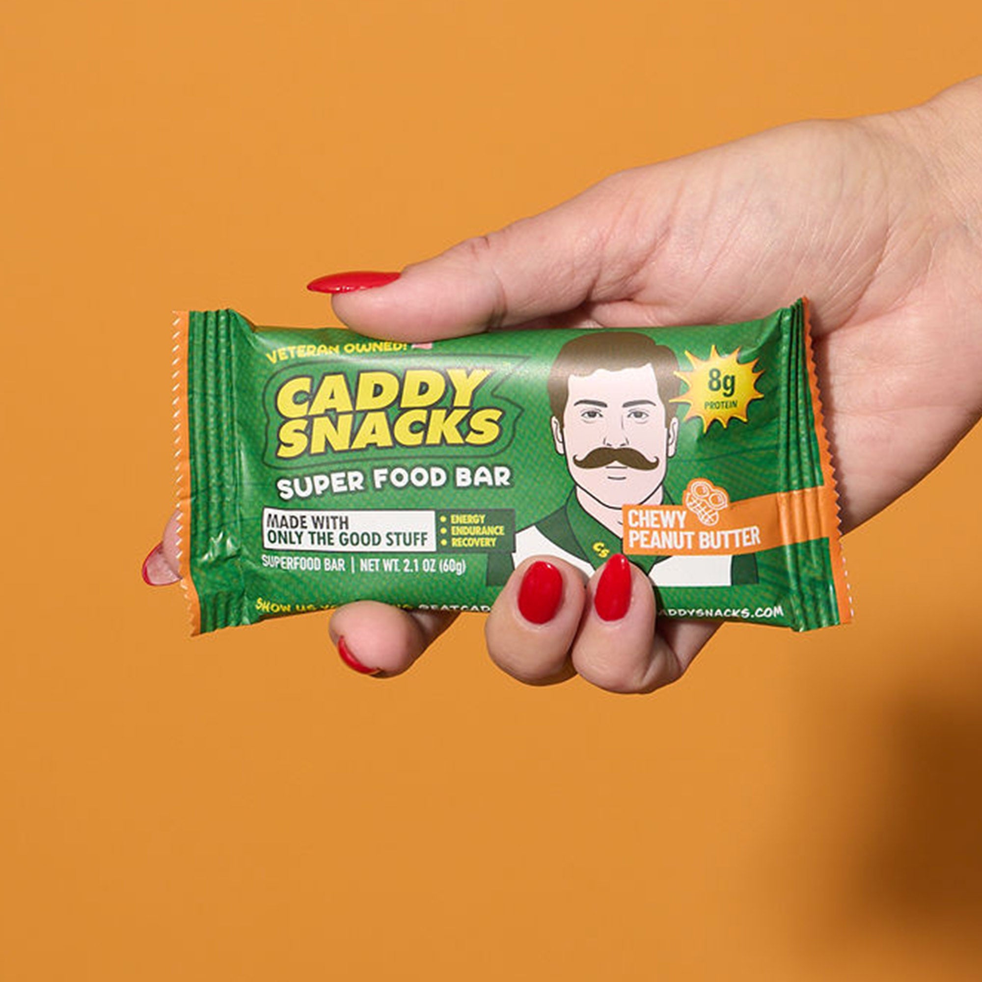 Chewy peanut butter snack bar held in hand, green wrapper